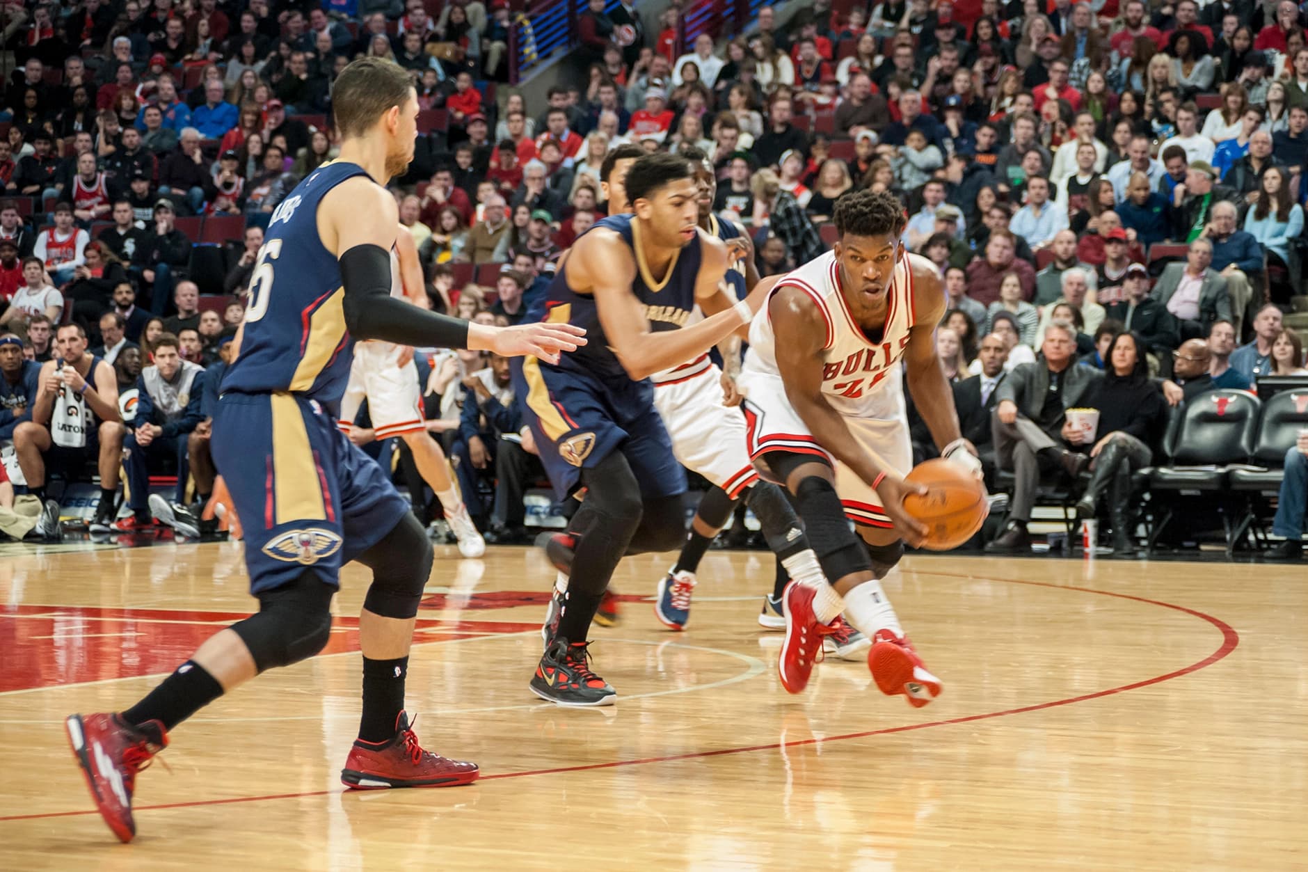 A tennis player dusting off his tennis racket with a brand advert behind him