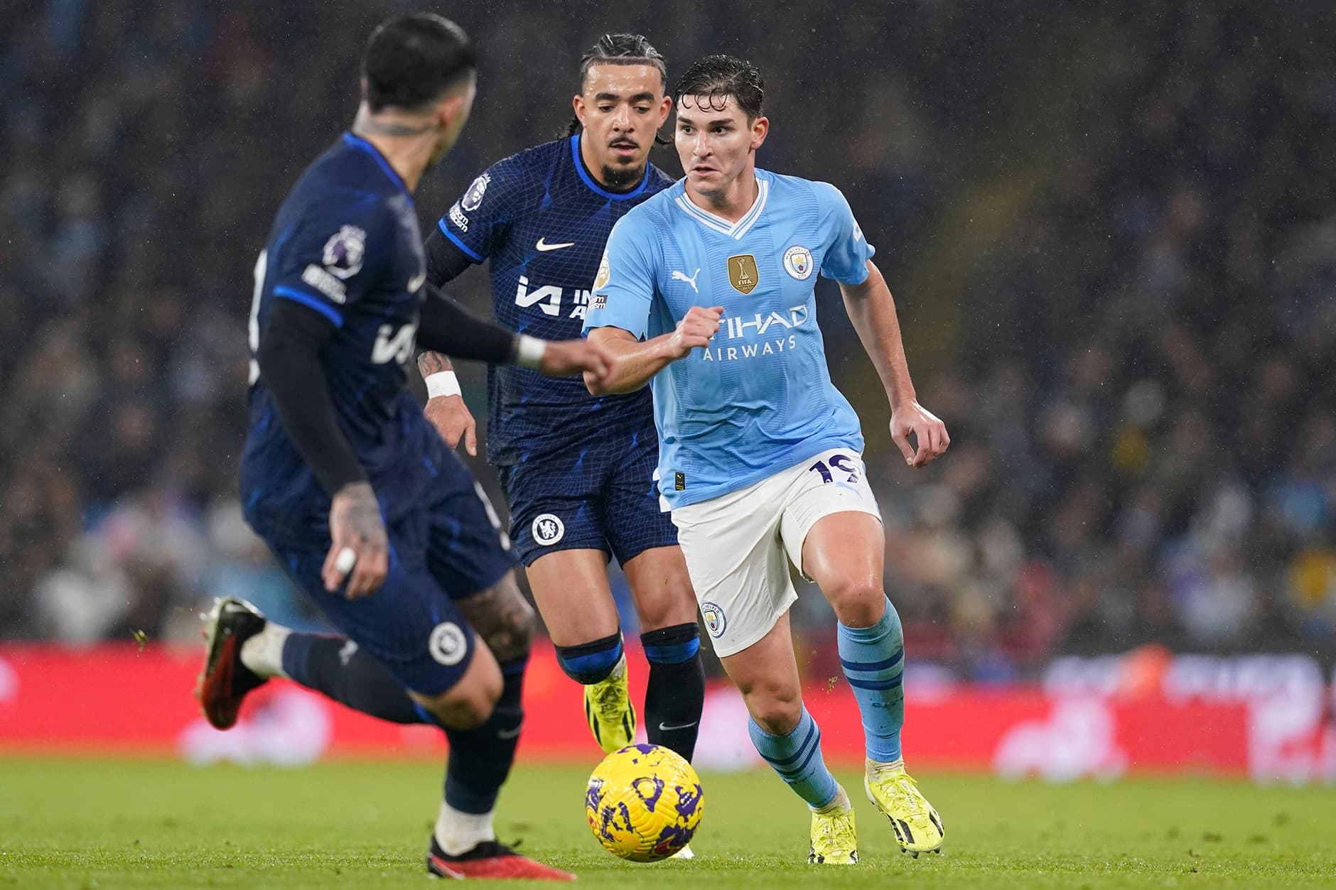 A football stadium brimming with fans with brands adverts all around